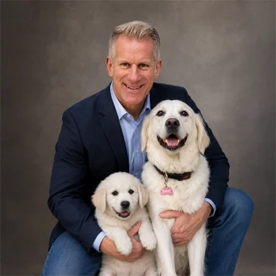 Dr.Michael Auer, a chiropractor at Spine Rehab Nation posing with two white dogs.